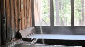 A wooden cabin interior with a bench, a window, and a sign on the wall. - Shibu Tatsunokan (Chino)