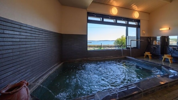 A hot tub with a view of the sea, a window, and a wooden bench. - Amigen (Toba)