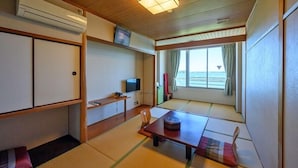 A room with tatami flooring, a television, a window with curtains, and a ceiling fan. - Amigen (Toba)