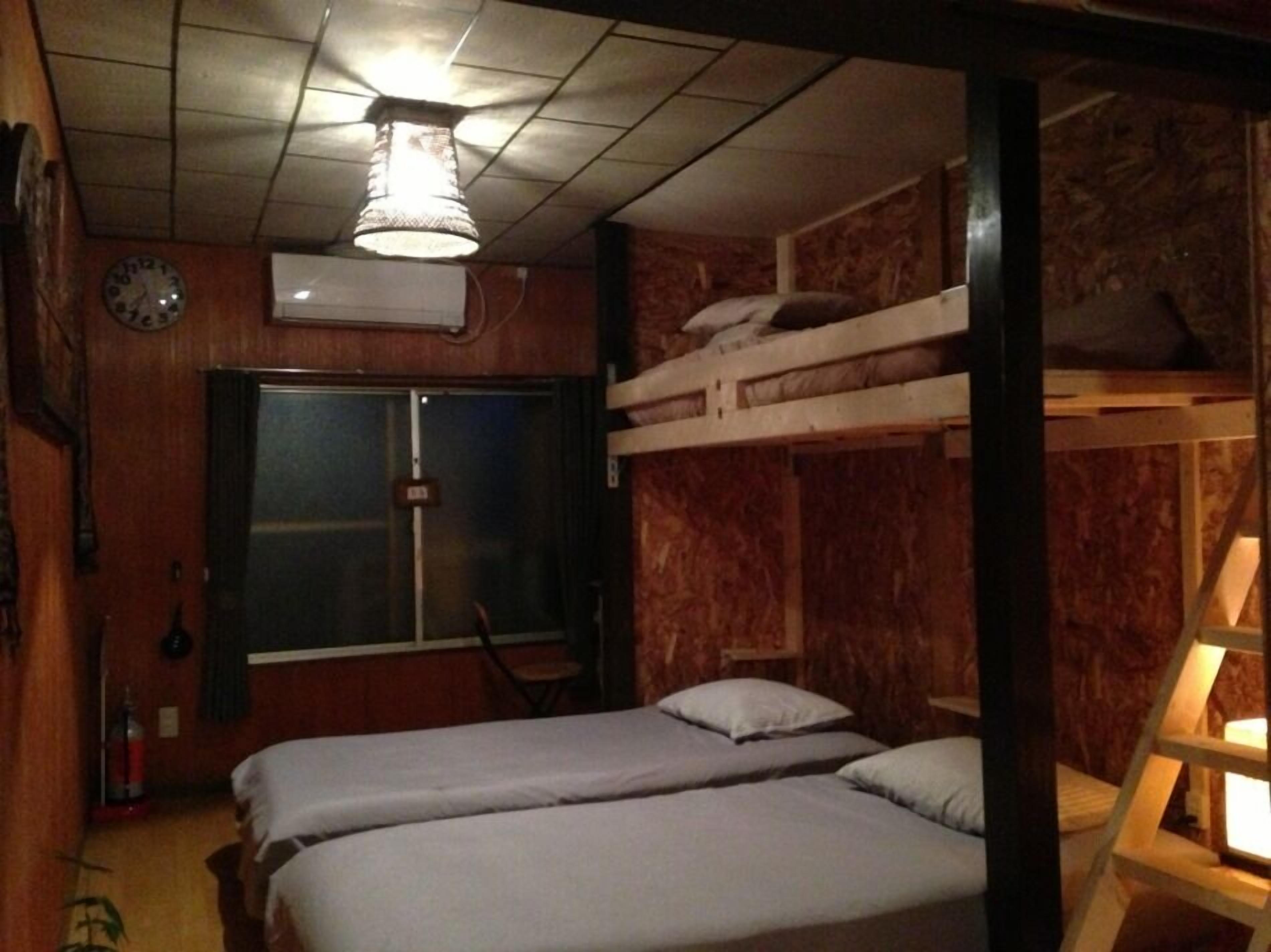 A room with bunk beds, a wooden wall, a clock, and a ceiling fan.