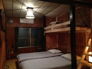 Une pièce avec des lits superposés, un mur en bois, une horloge et un ventilateur de plafond.