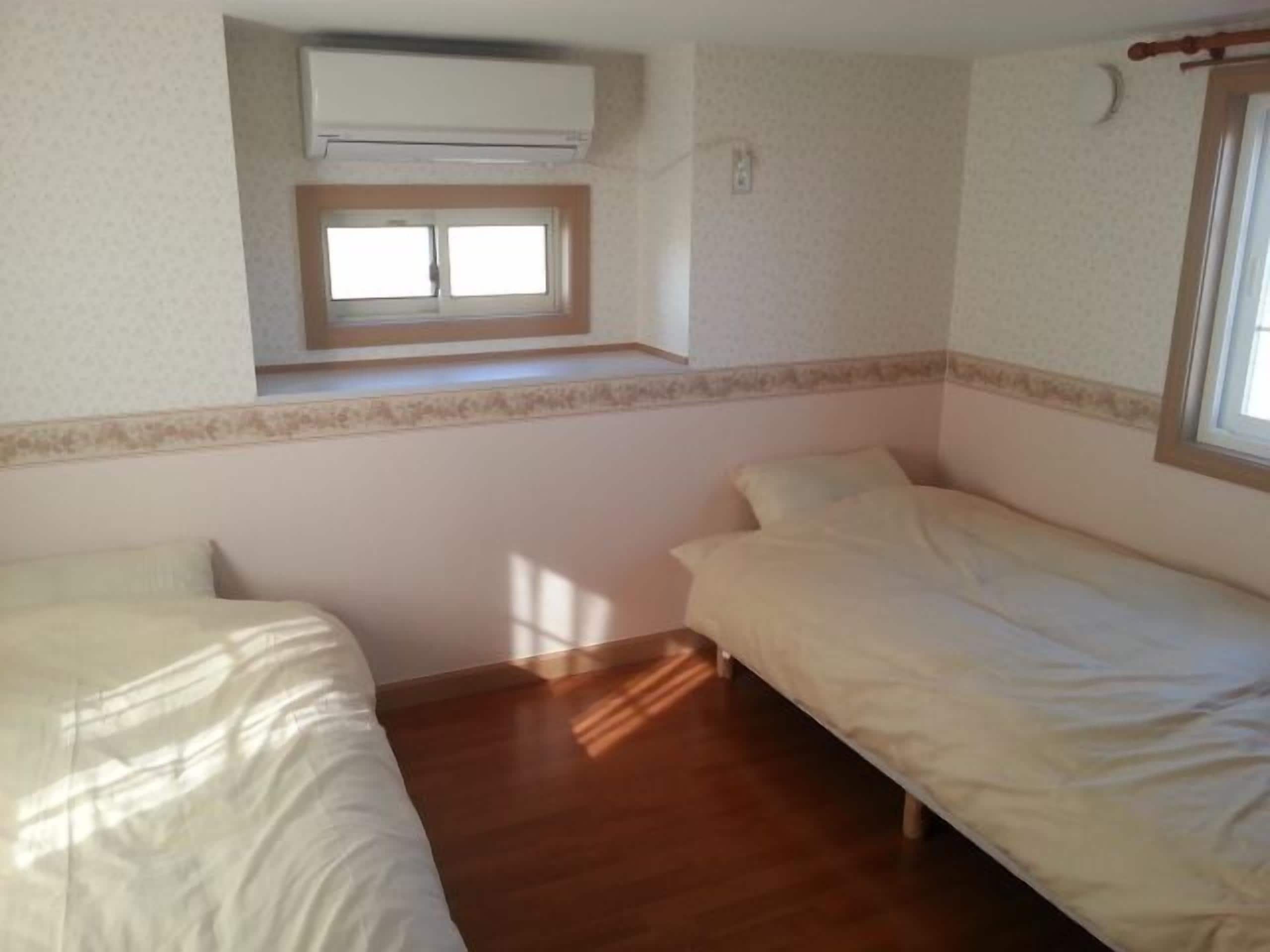 Una habitación con dos camas, una ventana y un aire acondicionado.