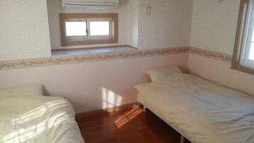 Una habitación con dos camas, una ventana y un aire acondicionado.