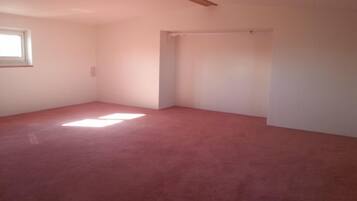 Una habitación con techo inclinado, una ventana y una puerta.