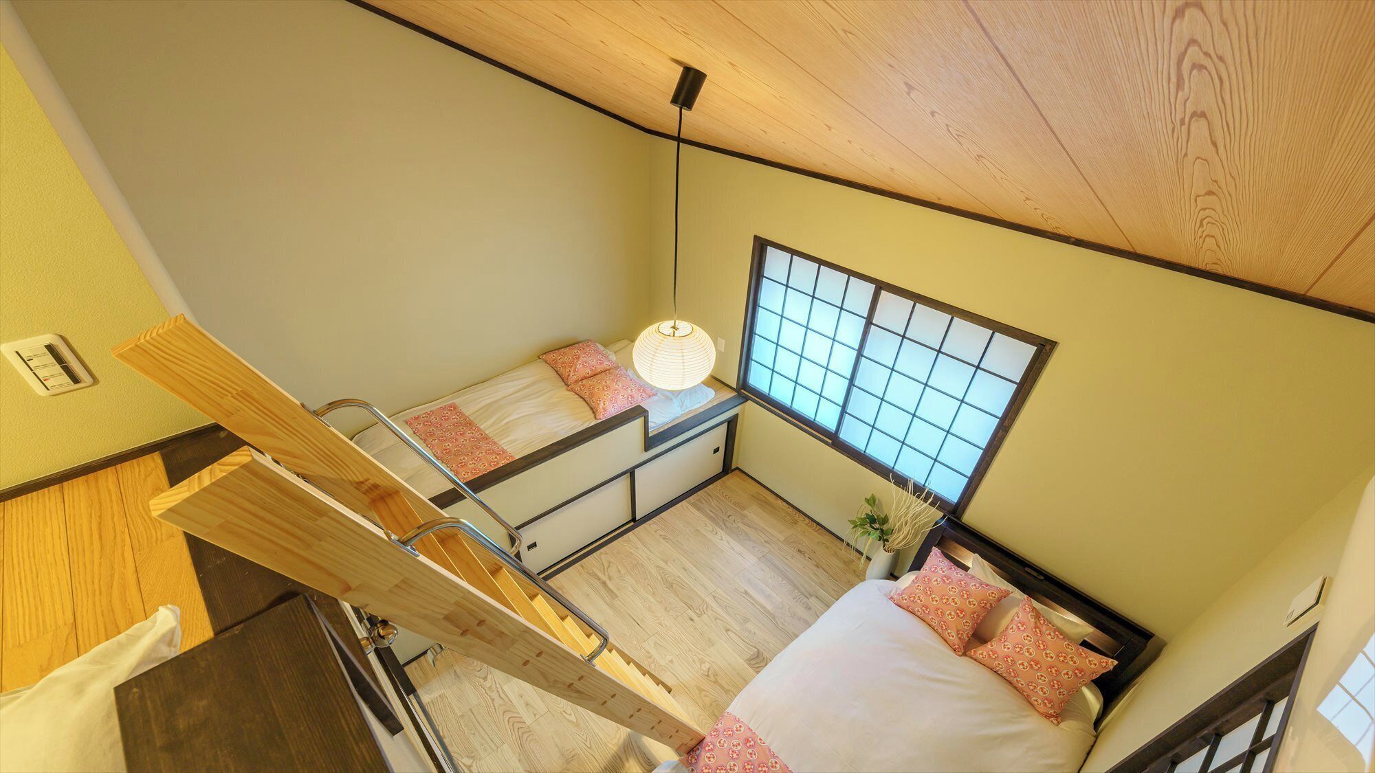 A compact room with a bunk bed, a small window with a grid pattern, a ceiling fan, and a wooden ladder.