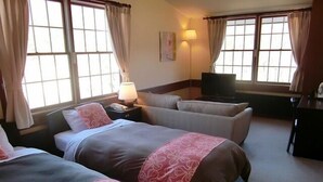 Una habitación de hotel con dos camas, un escritorio, una silla y un televisor.