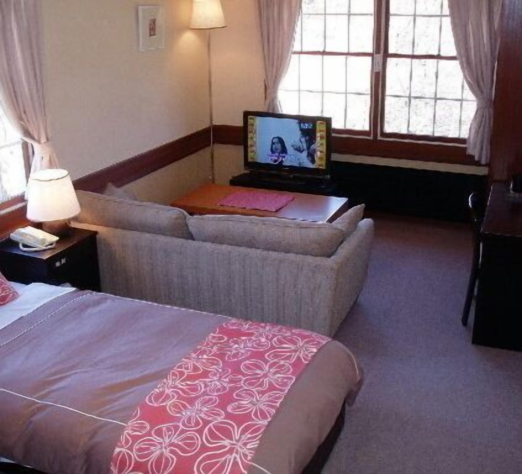 Una habitación de hotel con cama, sofá, televisor y escritorio.