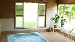 Una piscina interior con techo de madera, ventanas amplias y plantas en macetas.
