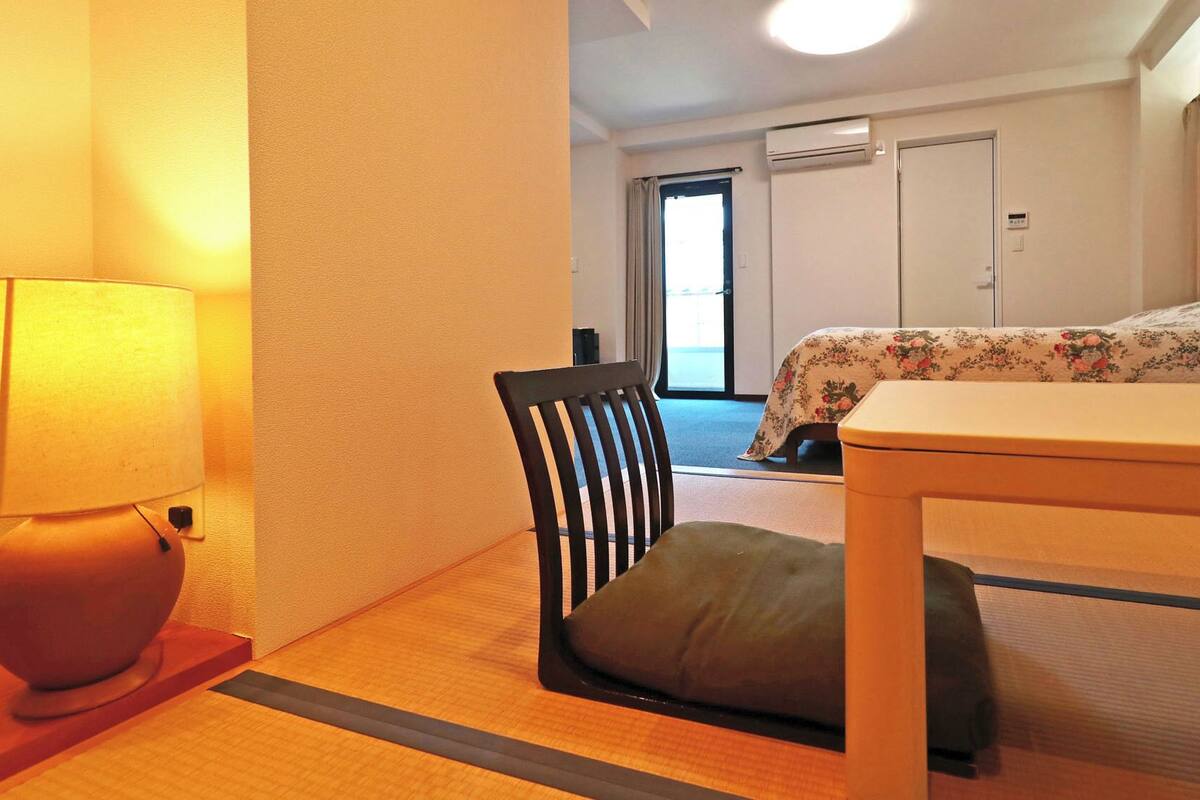 Una habitación de hotel con cama, una silla, una mesa, una lámpara y una puerta.