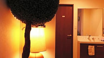 A bathroom with a tree-shaped lamp, a wooden door, and a mirror.