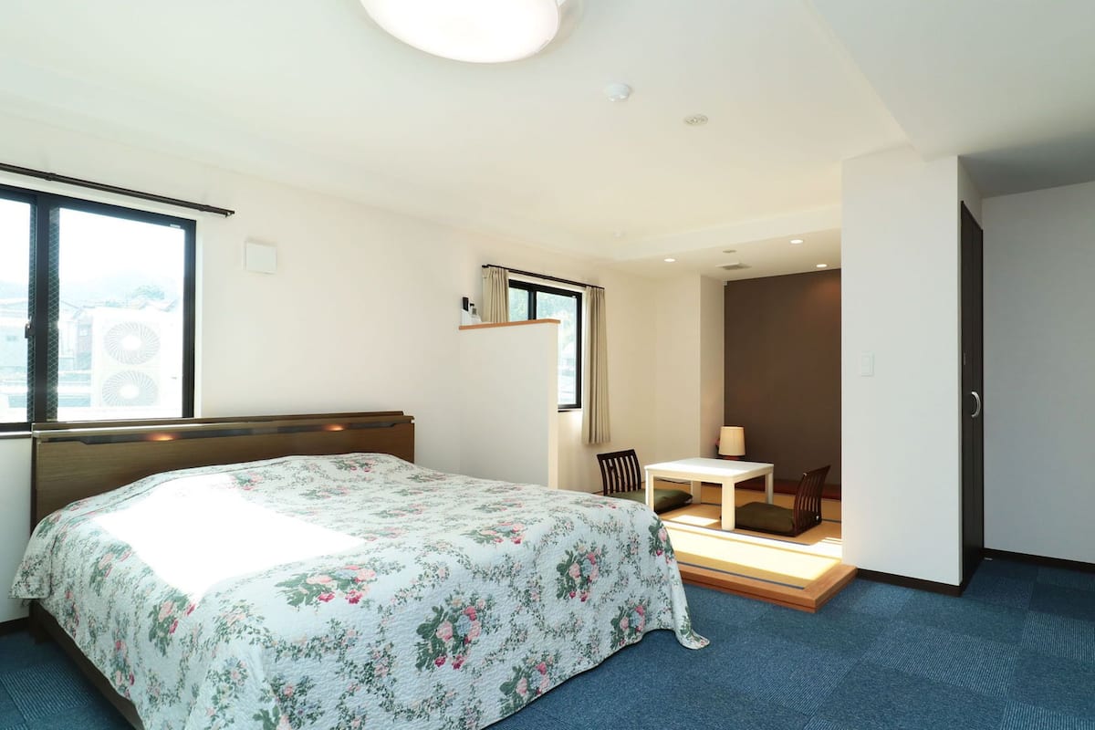 Una habitación de hotel con cama, escritorio, silla, televisor y ventana.