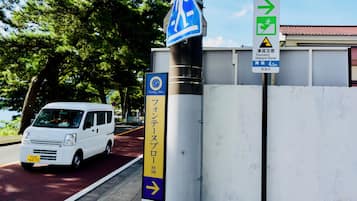 A white van parked on a road with a pedestrian crossing sign and a tsunami hazard zone sign.