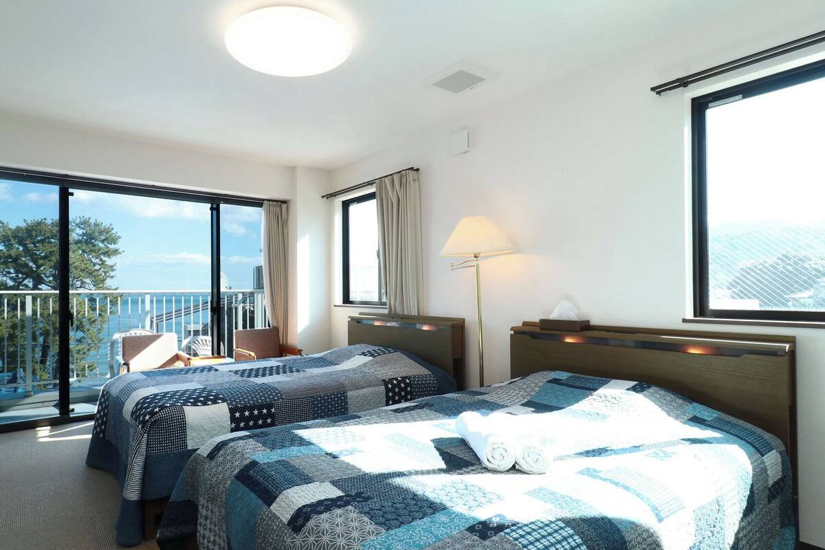 Habitación de hotel con dos camas, balcón, escritorio y una silla.