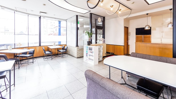 A modern interior with a long dining table, seating area, and a counter with a plant. - Hotel Goro Hakodate (Hakodate)