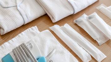 A neatly arranged set of white towels, a blue and white toothbrush, and a white dental floss package on a wooden surface.