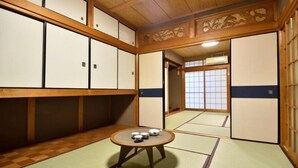 Une pièce de style japonais traditionnel, avec un sol recouvert de tatamis, des portes coulissantes et une petite table sur laquelle sont disposés des accessoires pour la cérémonie du thé.