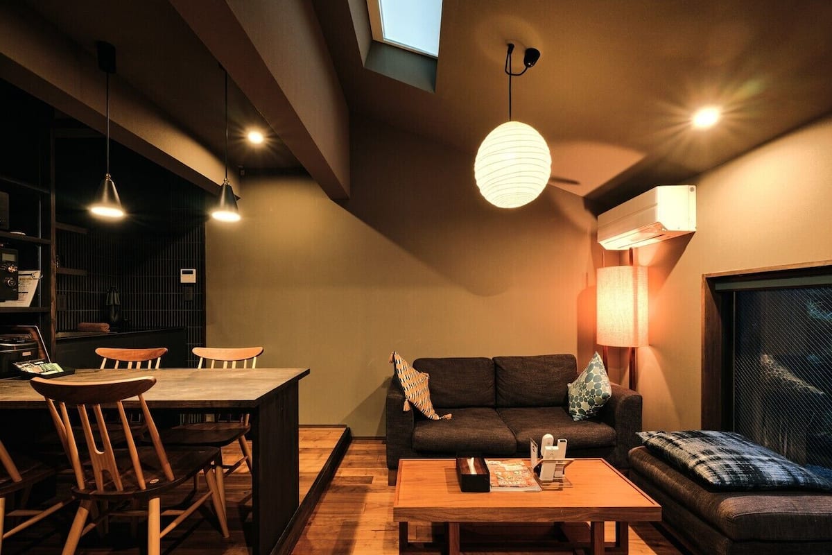 A modern living room with a dining area, wooden furniture, and a large window.
