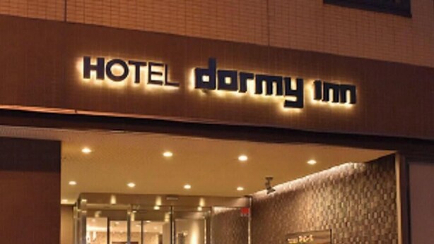 Hotellin sisäänkäynti, jonka yläpuolella on kyltti, jossa lukee: ”HOTEL DORMY INN”.