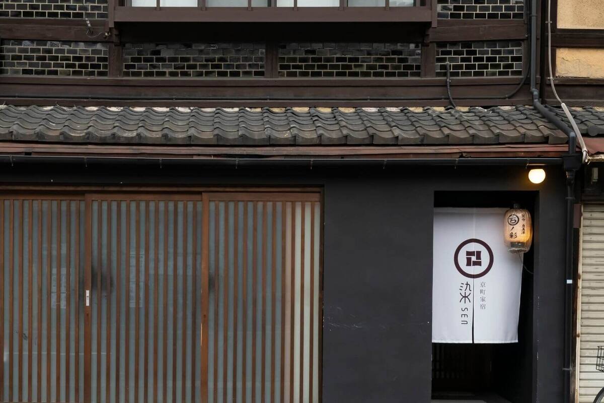 A traditional Japanese building with a large wooden door, a tiled roof, and a sign with Japanese characters.