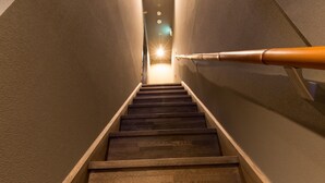 Uma escadaria com degraus de madeira e corrimão, que leva a uma área bem iluminada no topo.