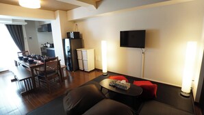 A living room with a sofa, a TV, a dining table with chairs, a kitchen area, and a refrigerator. - Asakusa Eight (Tokyo)