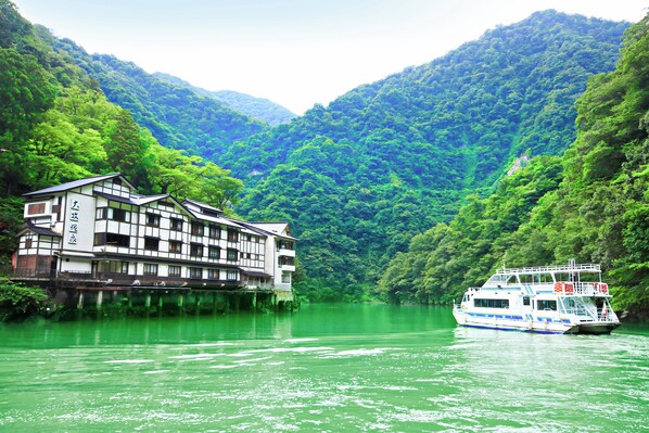 A riverboat with a traditional building on stilts beside it. - Oomaki Onsen (Nanto)