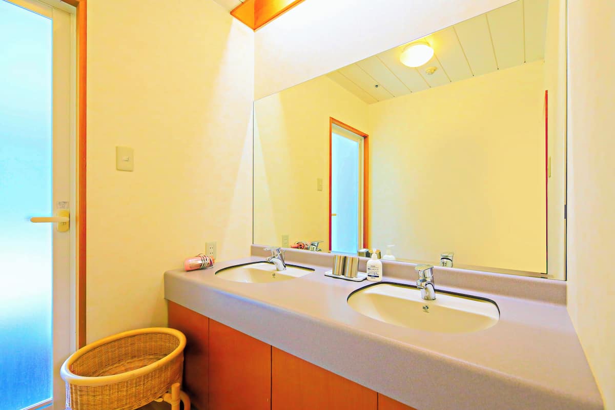 A bathroom with two sinks, a mirror, and a wicker basket.