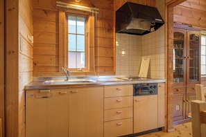 A wooden cabin-style kitchen with a sink, stove, and cabinets.