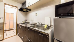 A modern kitchen with stainless steel appliances, wooden cabinets, and a built-in microwave. - Maiko-han Inn (Kyoto)