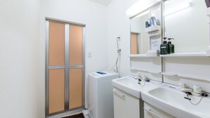 A bathroom with a washing machine, a sink, and a mirror. - Maiko-han Inn (Kyoto)