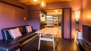 A modern living room with a sofa, a wooden table, and a TV. - Maiko-han Inn (Kyoto)