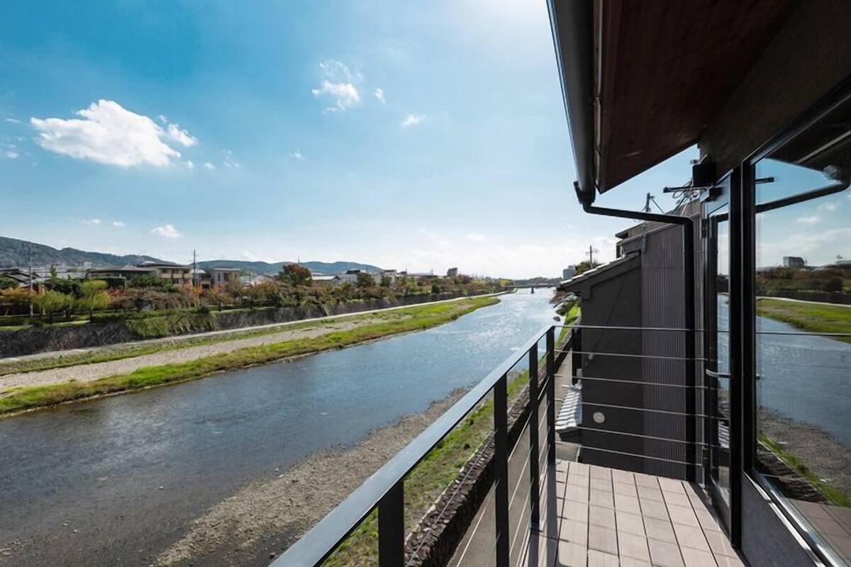 Ein Fluss mit einer Brücke, ein Gebäude mit einem Balkon und ein klarer Himmel.