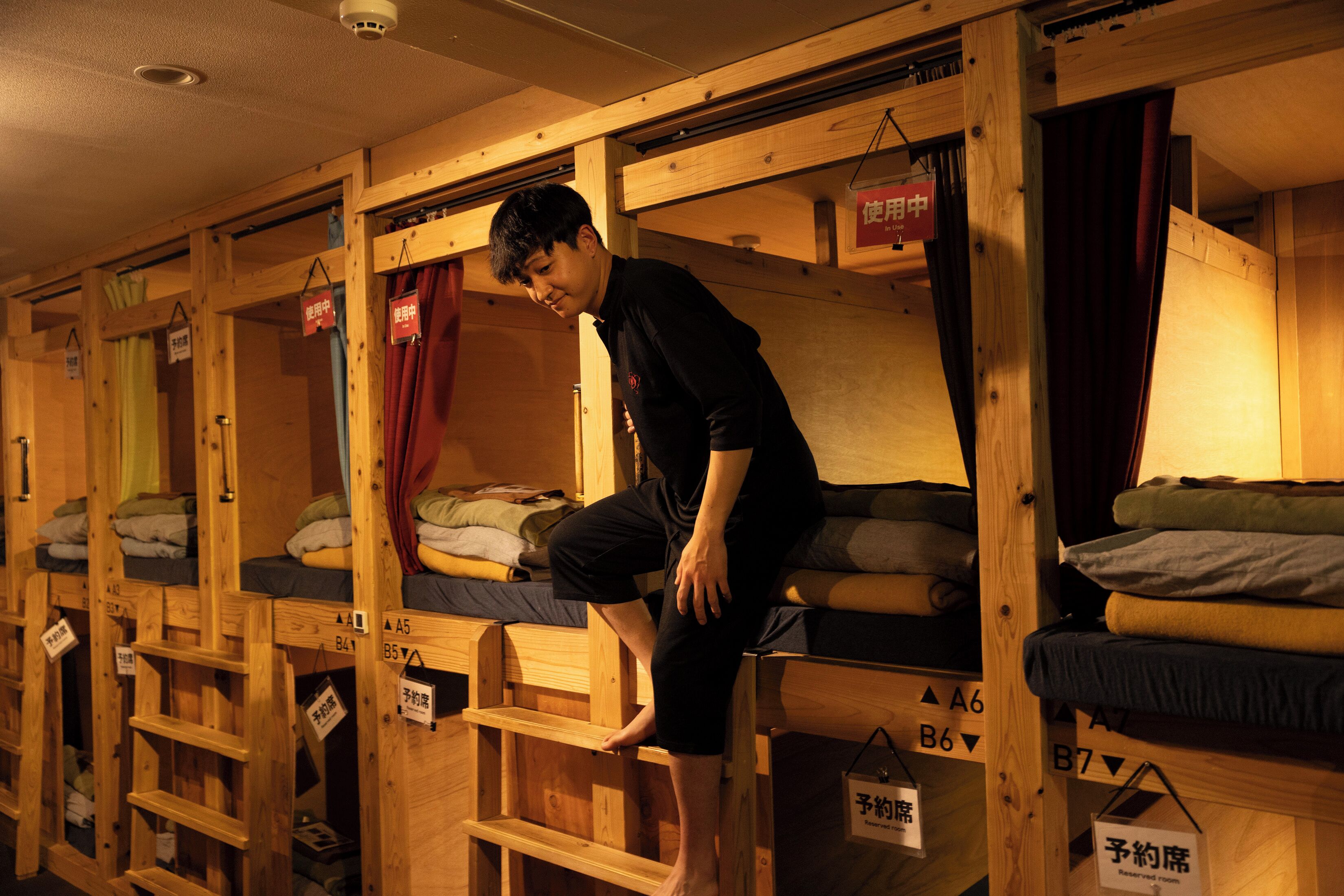 Une série de lits superposés en bois, chacun portant une étiquette indiquant le numéro de la chambre, ainsi qu’un panneau indiquant une chambre réservée.
