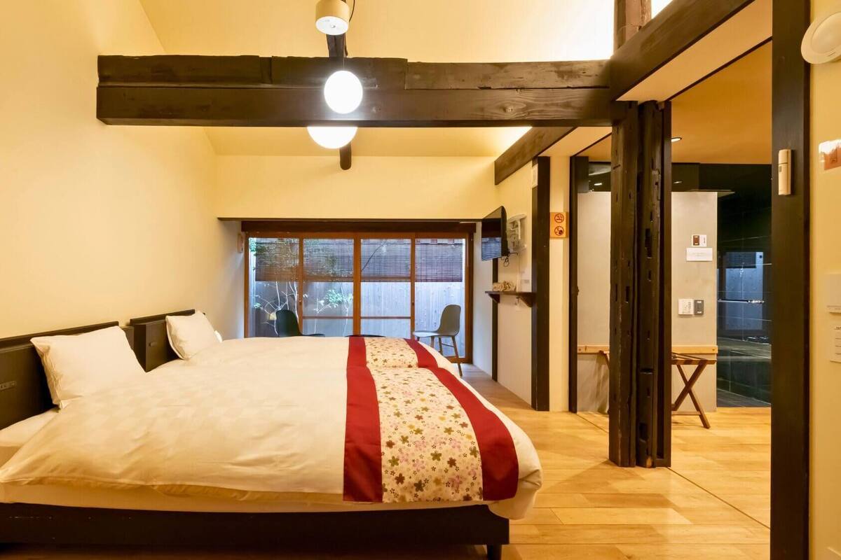 A bedroom with a bed, a window, and a door leading to a balcony.