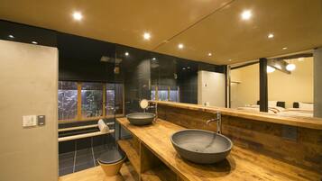 A modern bathroom with a large mirror, two sinks, and a wooden vanity.