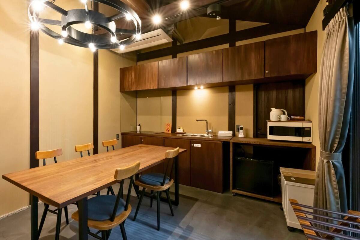 A compact kitchen with a wooden table and chairs, a microwave, and a sink.