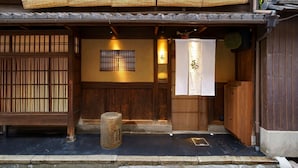 A traditional Japanese building with wooden sliding doors, a stone lantern, and a sign with Japanese characters. - Satoi Seishi Omiya Gojo (Kyoto)