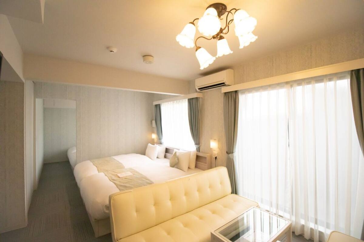 Una habitación de hotel con una cama, un sofá, una mesita de cristal y una araña.