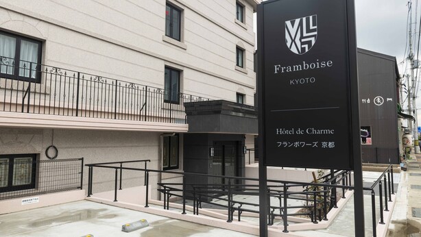 Een hotelschiltje met 'Framboise Kyoto' en 'Hotel de Charme', wat een hotel in Kyoto aangeeft.