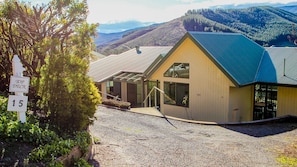 A modern building with a sloped roof, large windows, and a gravel driveway.
