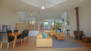 Ein geräumiger Wohnbereich mit Esstisch, Sofas, einer Treppe und einem Kaminofen.