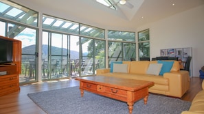 A spacious living room with a large sliding glass door leading to an outdoor area, a wooden coffee table, and a sofa with cushions.