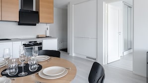 Een moderne keuken met een eethoek, witte kasten en een groot raam.