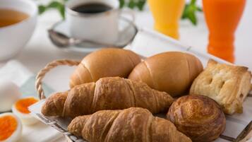 A breakfast setting with croissants, bread, and juice.