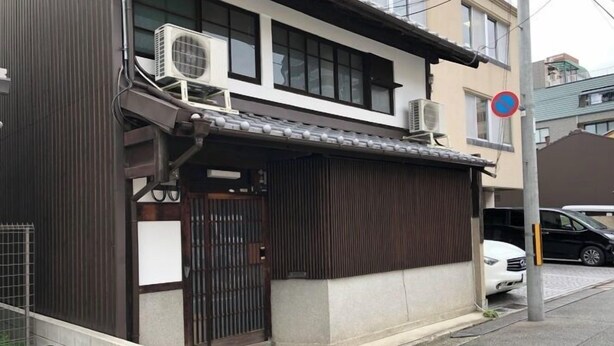 A residential building with a gated entrance, air conditioning units, and a no parking sign.