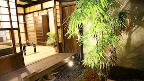 A traditional Japanese room with tatami flooring, a wooden bench, and a large potted plant.
