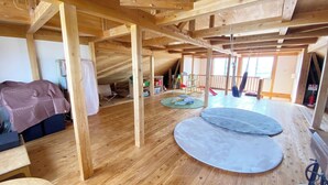 An attic room with exposed wooden beams, a loft bed, a hammock, and a play area with a slide. - Tabinoyado Tenohirani Taiyonoie (Tome)
