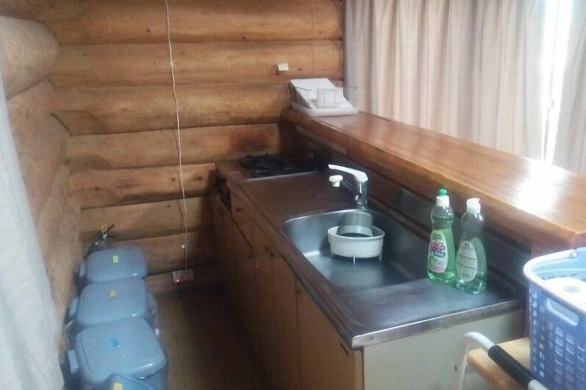 Cuina petita amb rentaplat, una superfície de treball i una finestra amb cortines.