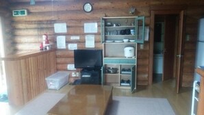 A log cabin interior with a wooden floor, a television, a shelf with dishes, and a clock on the wall. - Tm Resrot Kijimadaira (Kijimadaira)