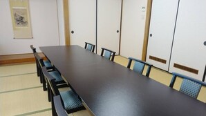 Un salón de conferencias con una larga mesa, sillas y puertas correderas tradicionales japonesas.